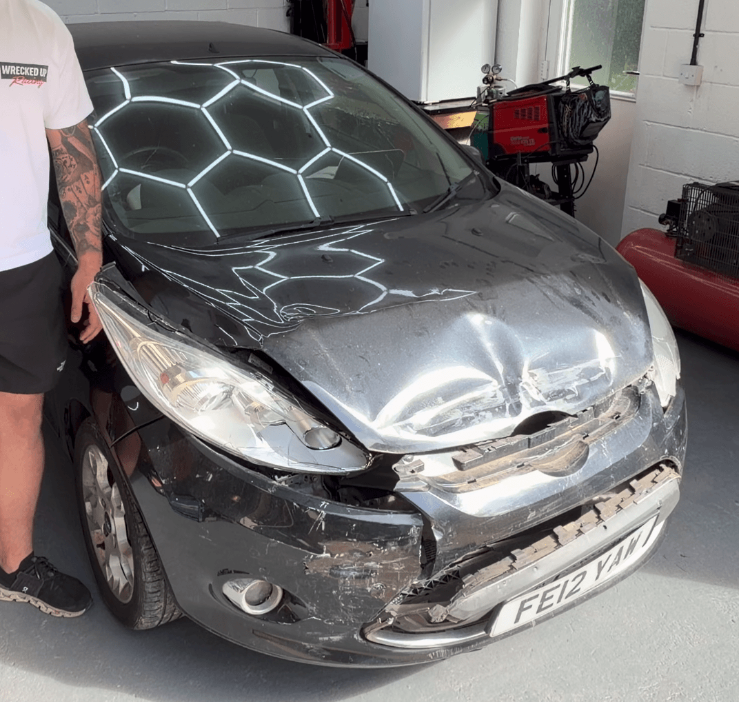 The actual black five-door Ford Fiesta with front-end damage in the Wrecked Up workshop